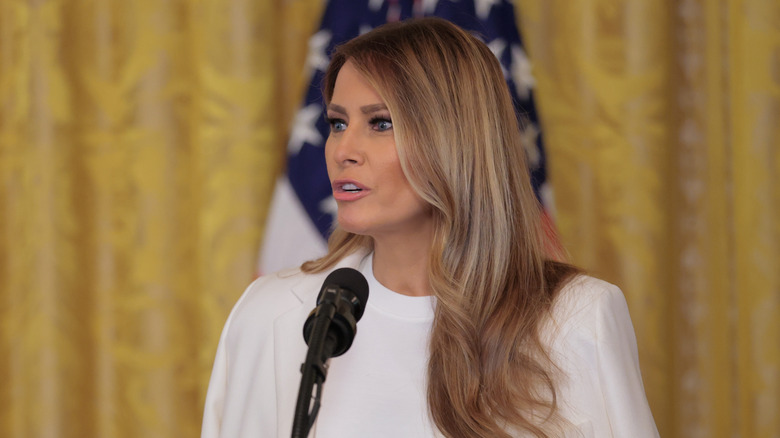 Melania Trump wearing white and speaking at a podium